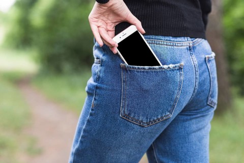 Woman removing smartphone from blue jeans pocket