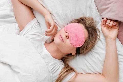 Woman wearing sleep mask her eyes top view