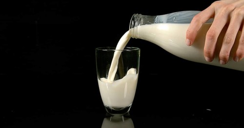 Milk being poured into Glass against black Background