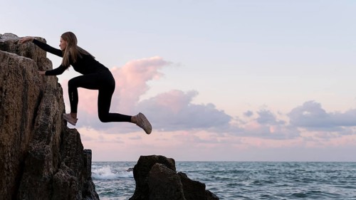 Side view woman climbing coast