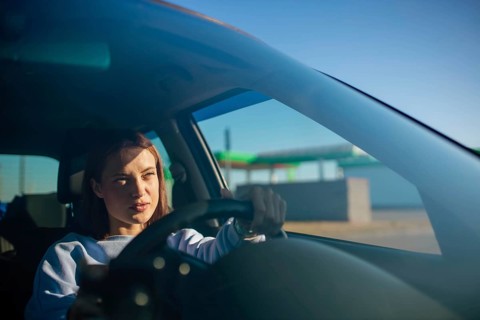 Young beautiful woman driver driving a car, happy trip, spring travel