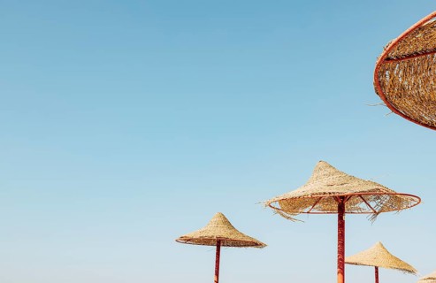 Looking up at wooden straw umbrella or thatched hut from below against beautiful cloudy blue sky