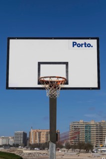 Basketball hoop in front of a blue sky with Porto lettering on the beach promenade in Matosinhos,