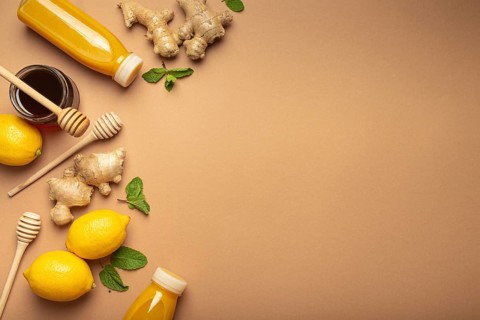 Orange detox drink, lemons, mint, ginger, honey in glass jar, honey wooden dippers top view. Food