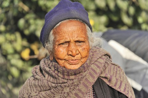 Portrait of an elderly woman with a serious expression and warm clothes outdoors, Chitwan National