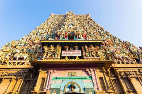 South gateway tower covered in statues of gods at the Meenakshi Amman Temple on a sunny day in