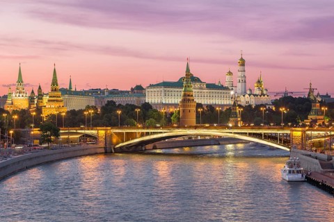Illuminated Moscow Kremlin and Moscow River with bridge in the summer evening. Pink sky. Russia