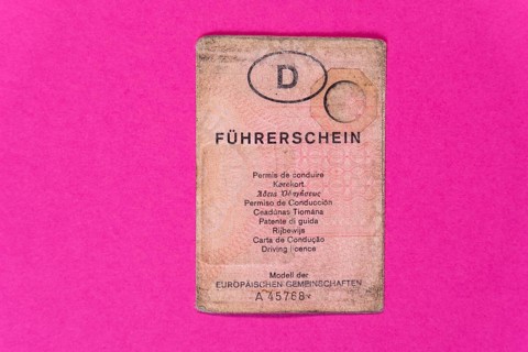Pink old driving licence against a pink background