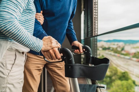 Close up unrecognizable senior couple holding hands while standing outside on the balcony