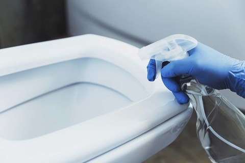 Close up on woman hand gloved in blue rubber protective gloves. Housewife cleaning toilet bowl,