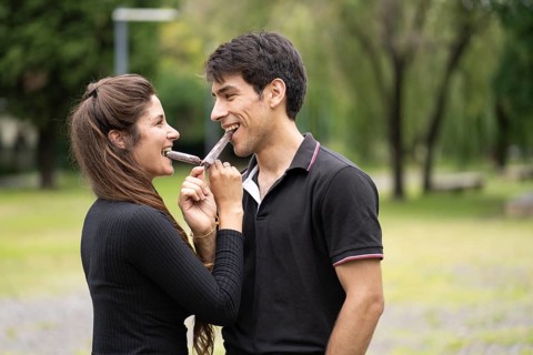 Young couple in love eating a popsicle in the park