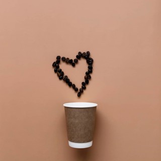 Beige background with paper coffee cup, coffee beans heart shape.