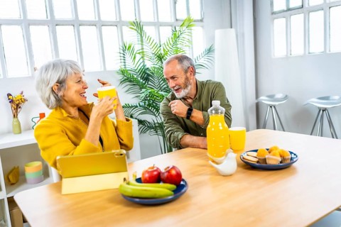 Happy senior couple enjoying a healthy breakfast in the living room at home