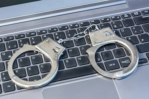 Handcuffs lying on computer keyboard as a symbol for cybercrime