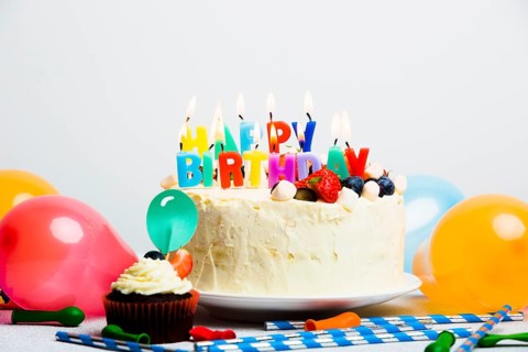 Tasty cake with berries happy birthday title near balloons