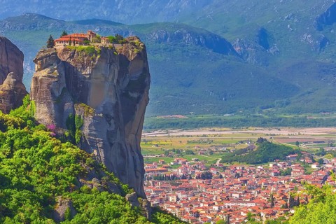 Holy Trinity Monastery on cliff rock top, Meteora, Greece and Kalampaka town in the valley