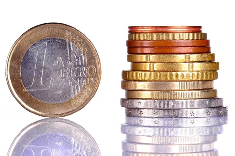 Close up of the oen Euro coin, next to a pile of coins