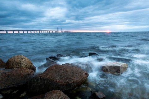 The view of the rough sea with a dramatic sky and a bridge in the background, Öresund Bridge,