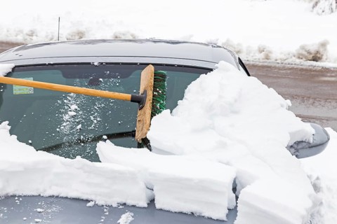 Sweeping a snow-covered car with a broom