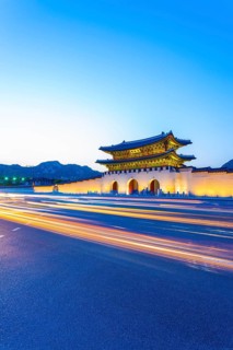 Colorful streaking car lights passing in front of lighted gate of Gwanghuamun, entrance to historic