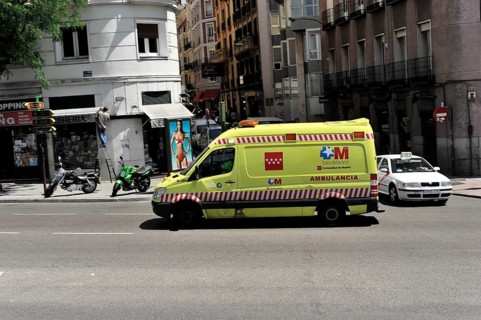 Madrid, Spain, Europe, Yellow ambulance on the street in a city, surrounded by buildings and other