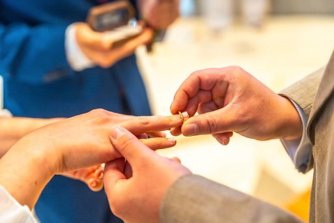 A man and woman are getting married and the man is putting a ring on the woman's finger