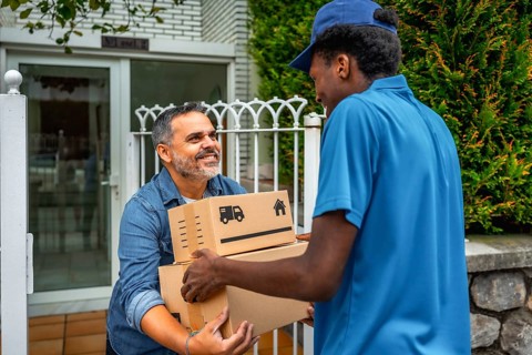 African delivery man giving packages to a costumer at home standing next to the entrance