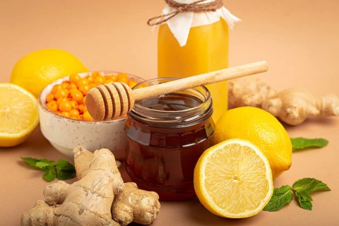 Composition with detox drink, sea buckthorn berries, lemons, mint, ginger, honey in glass jar. Food