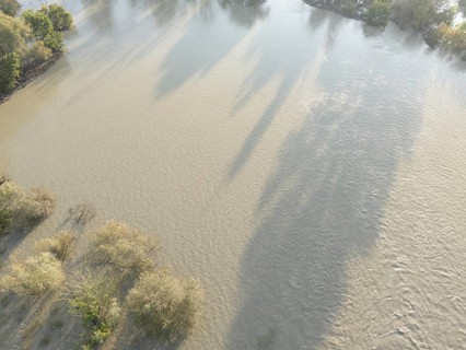Aerial view of muddy water flowing over the Po riverbanks covering the surrounding land, with a few