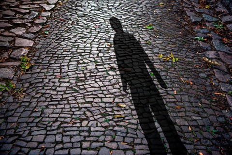 Human shadow on cobblestones at night, symbolic photo crime, burglar, creepy