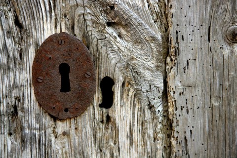 Key hole over aged gray old wood, rusty metal