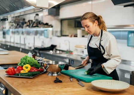 Side view female chef kitchen slicing vegetables
