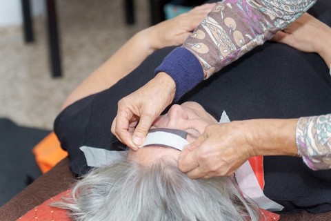 A therapist places a magnet on a patient's head during a biomagnetism session