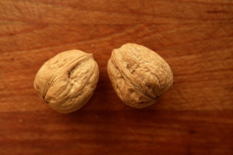 Two walnuts on a golden wood aged table