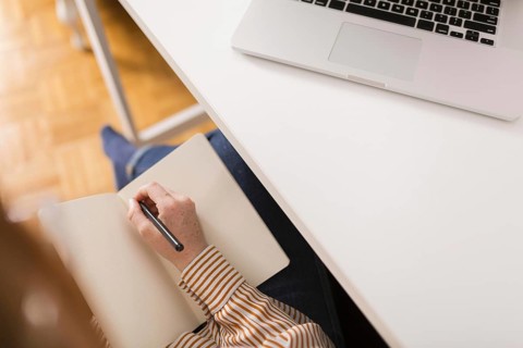High angle female teacher writing something agenda during online class