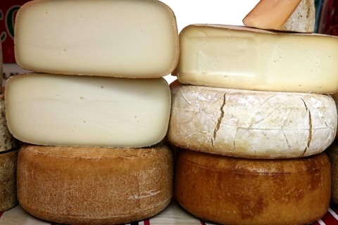 Aged french cheese wheels stacked on the marketplace