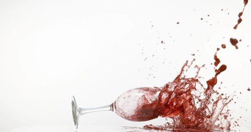 Glass of Red Wine Falling and Splashing against White Background
