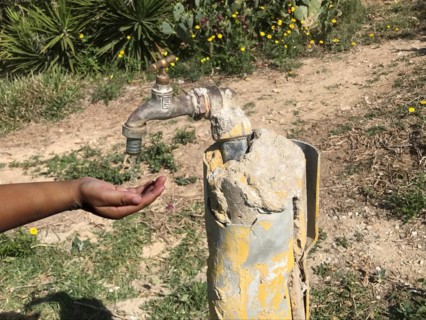 Water dripping from a tap flows into a child's hand