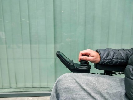 Close up of a disabled person hand driving electric wheelchair using joystick