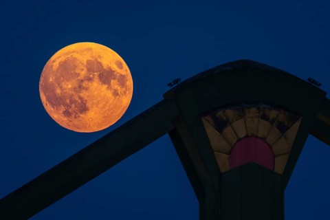 The full moon passes over the Flößerbrücke bridge in Frankfurt am Main. A super moon will shine