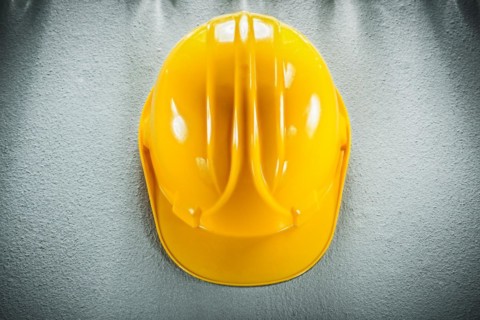 Yellow safety cap on concrete background View from above