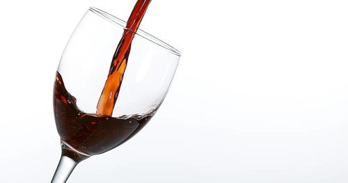 Red Wine being poured into Glass, against White Background