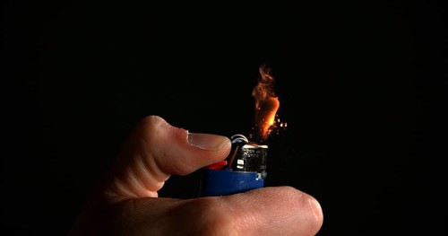 Lighter in Hand with Flame against Black background