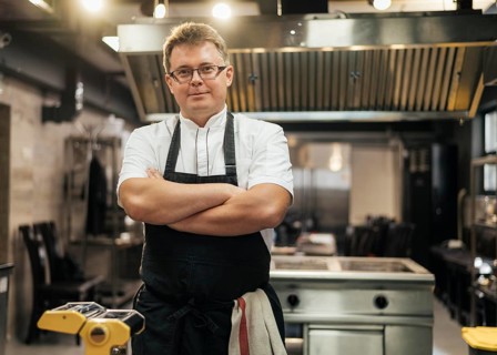 Front view male chef posing with arms crossed kitchen