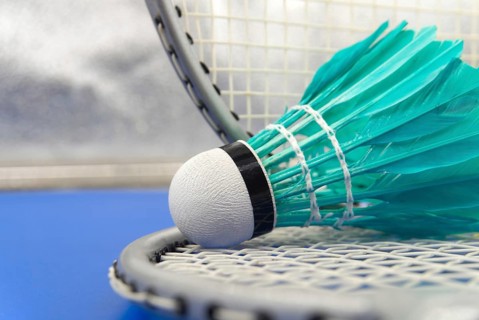 Badminton feather shuttlecocks in green with badminton rackets in a close up view