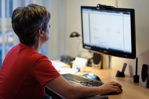 A woman sits at a desk and works on a PC