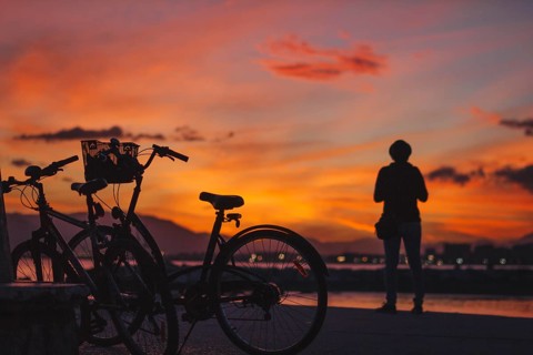 Person standing bicycle sunset
