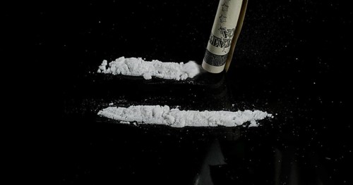 Dollar Bank notes and Powder Drug against Black Background
