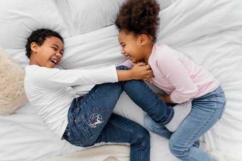 Top view two siblings playing bed home together