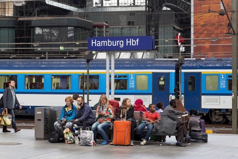 Hamburg, Germany, August 5, 2016: Group of people sitting under a signpost on the platform of the